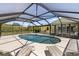 Relaxing in-ground pool inside screen enclosure with patio and lounge chairs at 10444 Willmington Blvd, Englewood, FL 34224