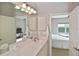 Bathroom featuring dual sinks with cabinets, vanity lighting, and a view into the bedroom at 1104 Auburn Cove Cir, Venice, FL 34292