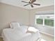 Cozy bedroom with plush carpeting, a ceiling fan, and a bright window with lush green view at 1104 Auburn Cove Cir, Venice, FL 34292