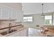 Well-lit kitchen featuring granite countertops, tile backsplash, and seamless access to the living room at 1104 Auburn Cove Cir, Venice, FL 34292
