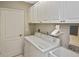 Functional laundry room with washer, sink, overhead cabinets, and a hanging rod at 1104 Auburn Cove Cir, Venice, FL 34292