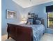 Charming bedroom with blue walls, a comfortable bed, and a window providing natural light at 114 Southampton N Pl # 237, Venice, FL 34293