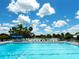 Community swimming pool surrounded by lounge chairs and lush landscaping under a bright, partly cloudy sky at 114 Southampton N Pl # 237, Venice, FL 34293
