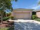 Beige two car garage with an arched top, lush landscaping, and visible house number on a sunny day at 11649 Tempest Harbor Loop, Venice, FL 34292
