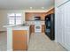 Open concept kitchen with light wood cabinets, stainless sink, white appliances, and tile flooring at 11649 Tempest Harbor Loop, Venice, FL 34292