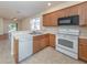 Kitchen featuring light wood cabinets, stainless sink, white appliances, and an open view to the living room at 11649 Tempest Harbor Loop, Venice, FL 34292