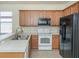 Kitchen featuring light wood cabinets, stainless sink, white appliances, and black refrigerator at 11649 Tempest Harbor Loop, Venice, FL 34292