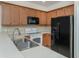 Kitchen with stainless steel sink, light wood cabinets, white countertops, and black microwave and refrigerator at 11649 Tempest Harbor Loop, Venice, FL 34292