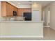 Kitchen featuring light wood cabinets, stainless sink, black refrigerator, and bar seating to the living room at 11649 Tempest Harbor Loop, Venice, FL 34292