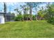 This grassy backyard has a screened-in patio and mature landscaping at 1214 Rumson Ct, North Port, FL 34288