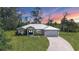 Beautiful home with a metal roof, manicured lawn, and a long driveway leading to a two-car garage at 1214 Rumson Ct, North Port, FL 34288