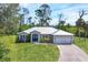 Beautiful home with a metal roof, manicured lawn, and a long driveway leading to a two-car garage at 1214 Rumson Ct, North Port, FL 34288