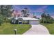 Beautiful home with a metal roof, manicured lawn, and a long driveway leading to a two-car garage at 1214 Rumson Ct, North Port, FL 34288