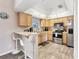 Bright kitchen with wood cabinets, stainless steel appliances, breakfast bar, and tile flooring at 1214 Rumson Ct, North Port, FL 34288