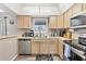 Well-lit kitchen with light wood cabinetry, stainless steel appliances, and durable flooring at 1214 Rumson Ct, North Port, FL 34288