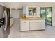Bright kitchen featuring tile flooring, wood countertops, stainless steel refrigerator, and sliding glass door to patio at 1240 Lucaya Ave, Venice, FL 34285