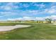Expansive golf course with a large sand trap, lake views, and modern houses in the distance at 12440 Wellen Golf St # 204, Venice, FL 34293