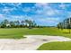 Scenic golf course featuring a sand trap, pristine green, and residential buildings in the background at 12440 Wellen Golf St # 204, Venice, FL 34293