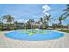 Community splash pad with vibrant blue and yellow flower design, surrounded by palm trees and shade structures at 12689 Sagewood Dr, Venice, FL 34293