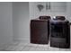Modern laundry room featuring sleek, dark-colored washer and dryer with tile flooring and overhead shelving at 12705 Pinnacle Ln, Venice, FL 34293