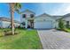 Charming two-story home featuring a paved driveway, well-manicured lawn, and a bright orange front door at 12816 Morning Mist Pl, Venice, FL 34293