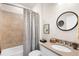 Cozy bathroom features shower with neutral tiles, shower curtain, and oval mirror above the sink at 13486 Nobilio St, Venice, FL 34293