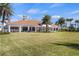 Beautiful clubhouse featuring a large lawn, covered patio, and stunning architecture surrounded by palm trees at 13486 Nobilio St, Venice, FL 34293