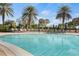 Large community pool surrounded by lounge chairs and blue umbrellas, great for relaxation at 13486 Nobilio St, Venice, FL 34293