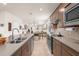 Galley kitchen featuring an island, stainless appliances, and open to the dining and living areas at 13486 Nobilio St, Venice, FL 34293