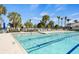 Beautiful swimming pool with palm trees, lounge chairs, and a clear blue sky on a sunny day at 13486 Nobilio St, Venice, FL 34293