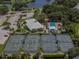 Aerial view featuring tennis courts, a clubhouse, a pool, and a parking area at 1531 Belfry Dr, Venice, FL 34292