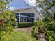 Back exterior of the home showcasing a sunroom with expansive windows and lush landscaping at 1531 Belfry Dr, Venice, FL 34292