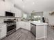 Bright kitchen features stainless steel appliances, white cabinets, countertops, and gray wood flooring at 15364 Isla Palma Ln, Nokomis, FL 34275