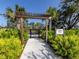 Playground entrance with lush landscaping and a wooden pergola, inviting children to play at 15364 Isla Palma Ln, Nokomis, FL 34275