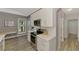 This modern kitchen features stainless steel appliances, white cabinetry, and a view to the front yard through a large window at 1799 Fountain View Cir, Venice, FL 34292