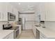 Bright kitchen with stainless steel appliances, white cabinets, light countertops, hardwood floors, and ceiling fan at 1799 Fountain View Cir, Venice, FL 34292