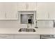 Bright kitchen featuring stainless steel sink, modern faucet, white cabinetry and quartz countertop at 1799 Fountain View Cir, Venice, FL 34292