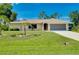 Well-maintained single-story home with an attached garage, lush lawn, and mature landscaping at 18375 Lamont Ave, Port Charlotte, FL 33948