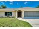 Charming single-story home with a well-manicured lawn, inviting entrance, and attached garage at 18375 Lamont Ave, Port Charlotte, FL 33948