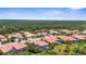 An aerial view showcasing the neighborhood's tile roofs, landscaping, with a lake and forest in the background at 186 Portofino Dr, Nokomis, FL 34275