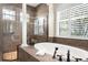 Elegant bathroom featuring a soaking tub, walk-in shower, and plantation shutters for natural light at 186 Portofino Dr, Nokomis, FL 34275