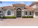 Close-up of home's entrance featuring a brick driveway, manicured shrubs, and a striking arched entryway at 186 Portofino Dr, Nokomis, FL 34275