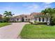 Inviting home showcasing a brick driveway, green lawn, and lush tropical landscaping accentuating the facade at 186 Portofino Dr, Nokomis, FL 34275