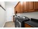 Well-equipped laundry room with dark countertops, wooden cabinetry, sink and modern washer and dryer at 186 Portofino Dr, Nokomis, FL 34275