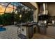 Covered outdoor kitchen with granite countertops, stainless steel grill, and bar seating, overlooking the screened pool area at 186 Portofino Dr, Nokomis, FL 34275