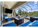 Screened patio featuring comfortable blue furniture, a fire pit, and a TV, perfect for outdoor entertaining at 186 Portofino Dr, Nokomis, FL 34275