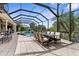 Screened-in patio with a dining table, bar and a beautiful view of the pool and lush greenery at 186 Portofino Dr, Nokomis, FL 34275