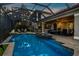 Tranquil pool area at dusk with illuminated patio and lush landscaping, ideal for relaxation and evening gatherings at 186 Portofino Dr, Nokomis, FL 34275