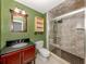 Updated bathroom featuring a cherry vanity, shower with a glass door, and natural colored tile at 2020 E Crest Dr, Englewood, FL 34223