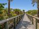 Picturesque beach boardwalk surrounded by tropical foliage and palm trees leads to the white sands and blue ocean at 2020 E Crest Dr, Englewood, FL 34223